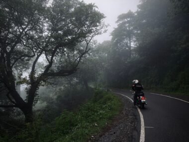 "Motorcyclist riding through monsoon rain on Indian highway"