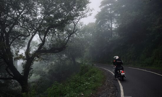 "Motorcyclist riding through monsoon rain on Indian highway"